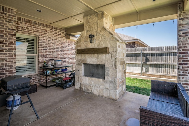 view of patio featuring an outdoor stone fireplace and area for grilling