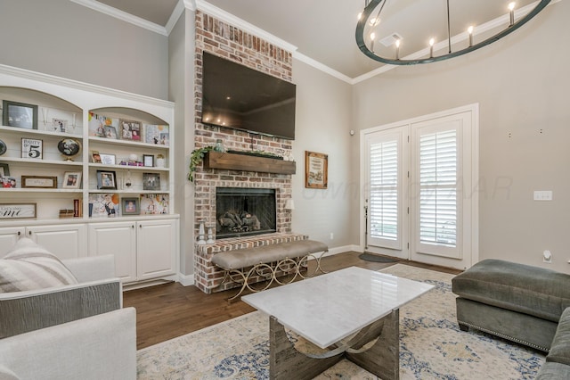 living room with a fireplace, crown molding, dark wood-type flooring, and an inviting chandelier