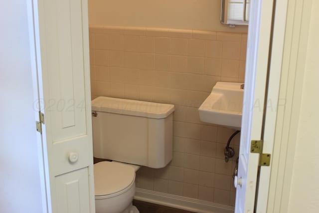 bathroom with toilet, tile walls, and sink