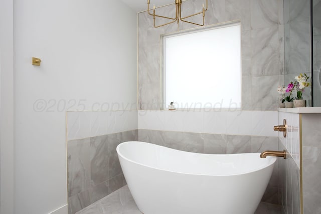 9800 Barton Springs Dr, Amarillo, TX 79119 - bathroom featuring tile walls, a freestanding bath, a chandelier, and marble finish floors