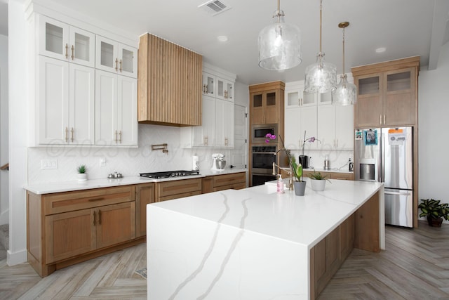 9800 Barton Springs Dr, Amarillo, TX 79119 - kitchen with appliances with stainless steel finishes, decorative backsplash, an island with sink, hanging light fixtures, and glass insert cabinets