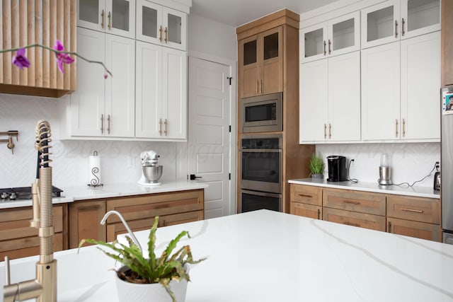 9800 Barton Springs Dr, Amarillo, TX 79119 - kitchen with decorative backsplash, appliances with stainless steel finishes, glass insert cabinets, light stone countertops, and white cabinetry