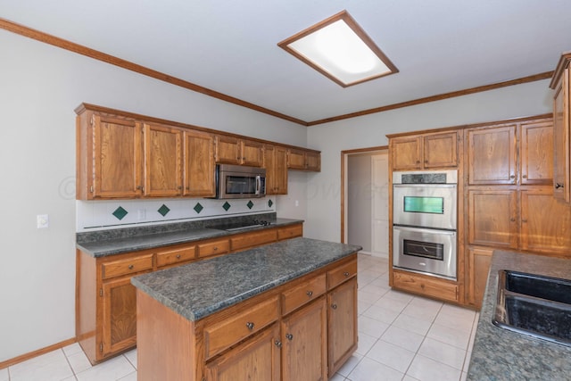 kitchen with dark countertops, crown molding, light tile patterned floors, appliances with stainless steel finishes, and brown cabinetry