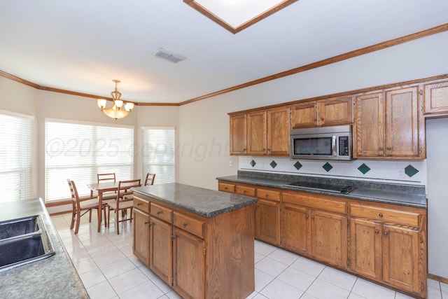 kitchen featuring visible vents, stainless steel microwave, brown cabinetry, black electric cooktop, and a chandelier