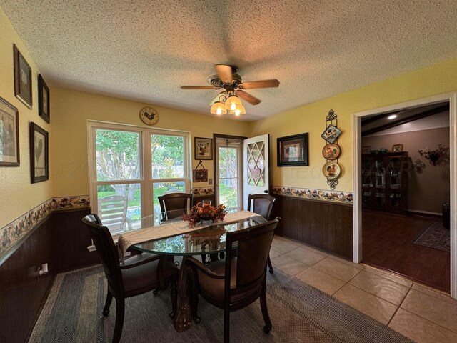 7204 SW 39th Ave, Amarillo, TX 79109 - tiled dining area with wainscoting, ceiling fan, healthy amount of natural light, a textured ceiling, and wooden walls