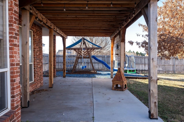 view of patio featuring a trampoline, a fenced backyard, and a playground