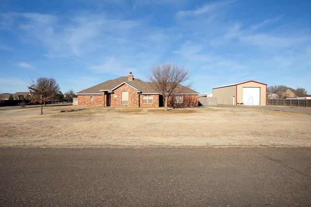 ranch-style house featuring an outbuilding, driveway, fence, brick siding, and a chimney