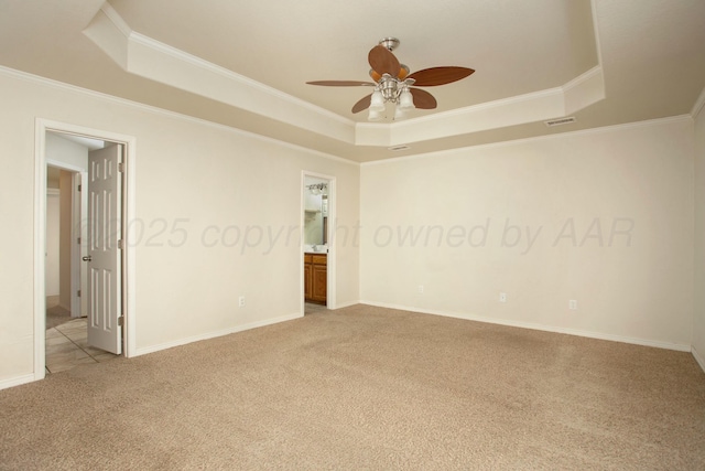 spare room with a ceiling fan, visible vents, crown molding, a raised ceiling, and light colored carpet