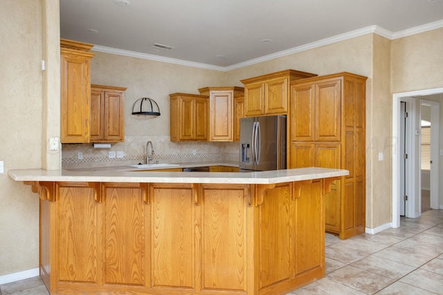 kitchen featuring light countertops, a breakfast bar area, stainless steel fridge, and a sink