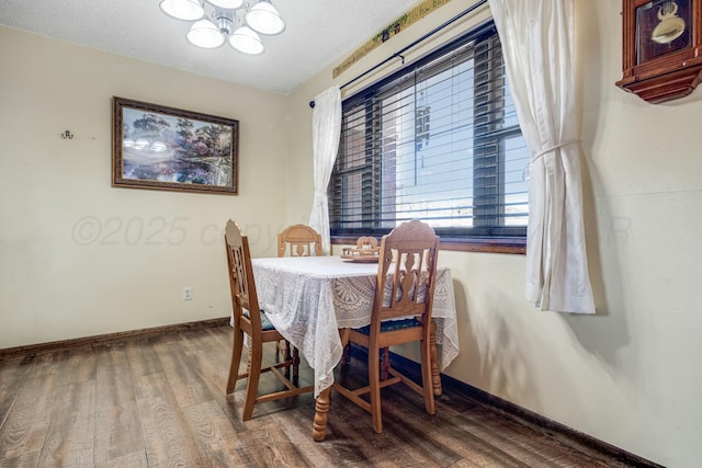 dining room with a chandelier, a textured ceiling, baseboards, and wood finished floors