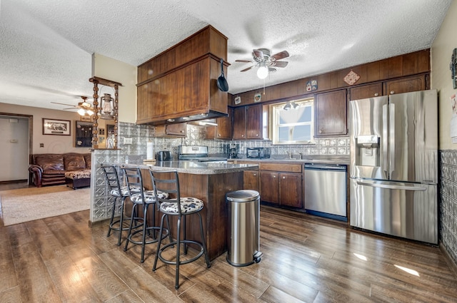 kitchen with appliances with stainless steel finishes, backsplash, and dark wood finished floors