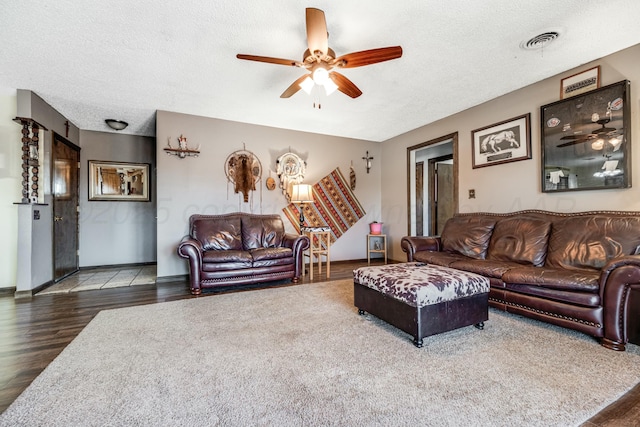 living area with a textured ceiling, ceiling fan, wood finished floors, visible vents, and baseboards