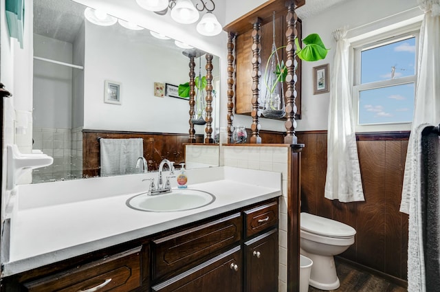 bathroom featuring a textured ceiling, toilet, a wainscoted wall, wood walls, and vanity