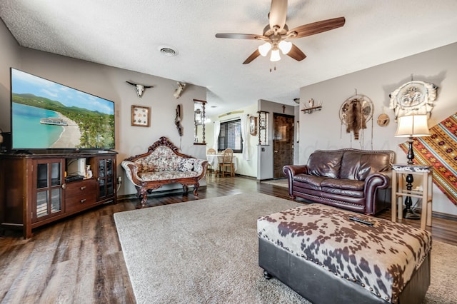 living area featuring visible vents, a ceiling fan, a textured ceiling, wood finished floors, and baseboards