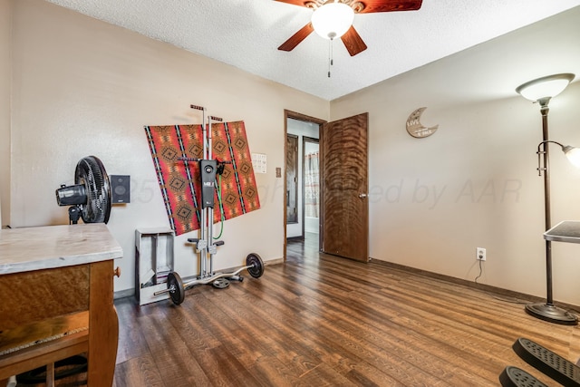 interior space featuring ceiling fan, a textured ceiling, baseboards, and wood finished floors