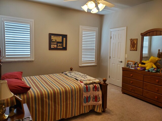 bedroom featuring ceiling fan, multiple windows, and light carpet