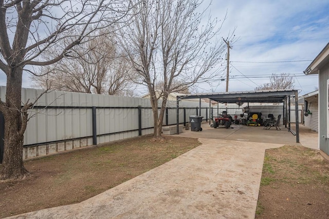 view of yard featuring a fenced backyard, a carport, and concrete driveway