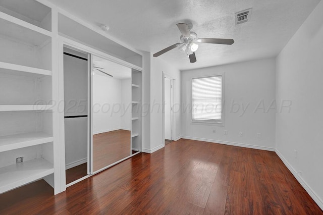 unfurnished bedroom featuring a textured ceiling, ceiling fan, wood finished floors, visible vents, and baseboards