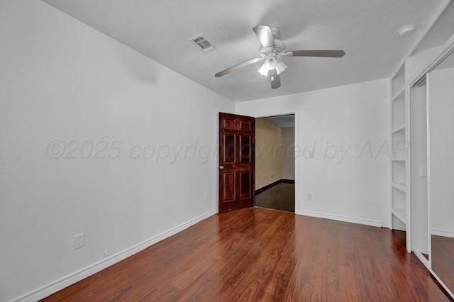 empty room with baseboards, wood finished floors, visible vents, and a ceiling fan