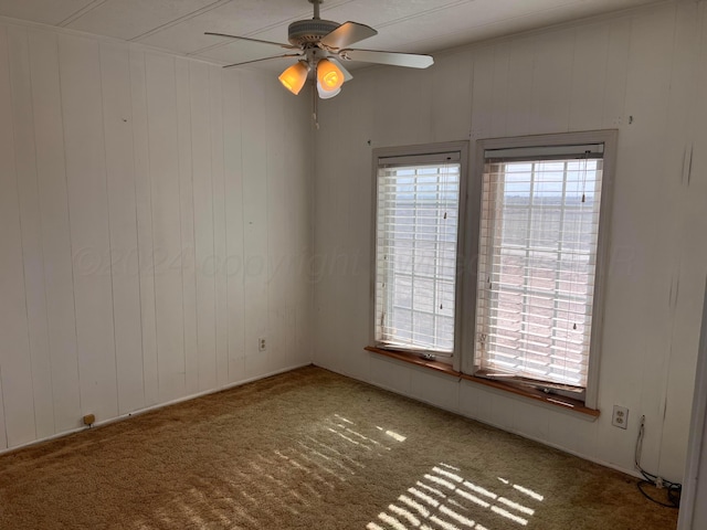 unfurnished room featuring carpet floors, ceiling fan, and wooden walls