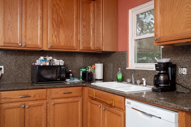 kitchen with black microwave, a sink, dishwasher, brown cabinetry, and backsplash