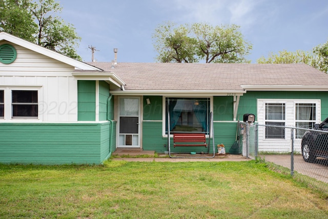 ranch-style home with fence, a shingled roof, and a front lawn