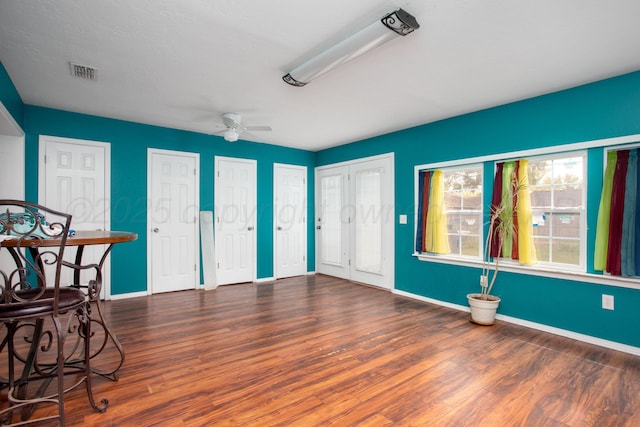 interior space featuring baseboards, ceiling fan, wood finished floors, and visible vents