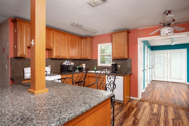 kitchen featuring a ceiling fan, visible vents, tasteful backsplash, wood finished floors, and white appliances