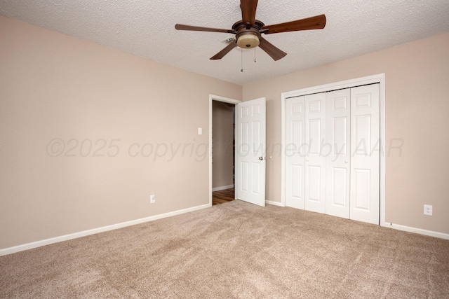 unfurnished bedroom with a closet, baseboards, a textured ceiling, a ceiling fan, and carpet
