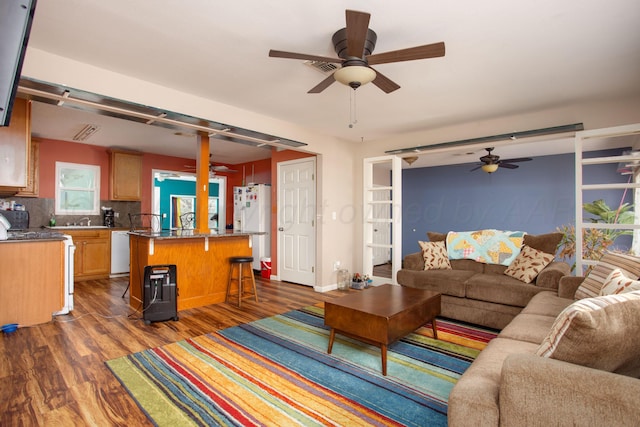 living room featuring a ceiling fan and dark wood-type flooring