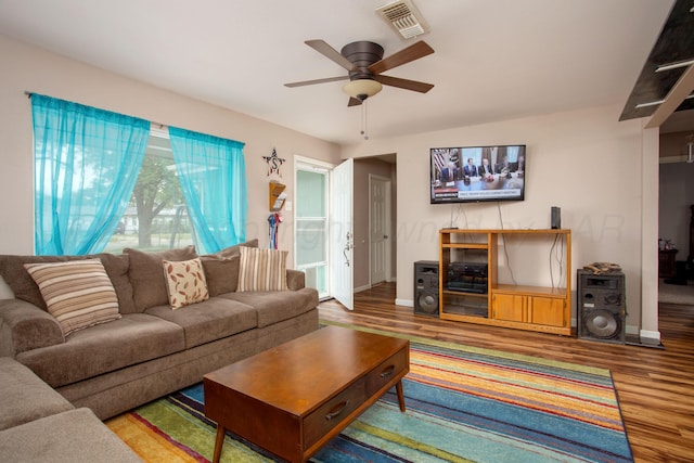 living room with a ceiling fan, baseboards, visible vents, and wood finished floors