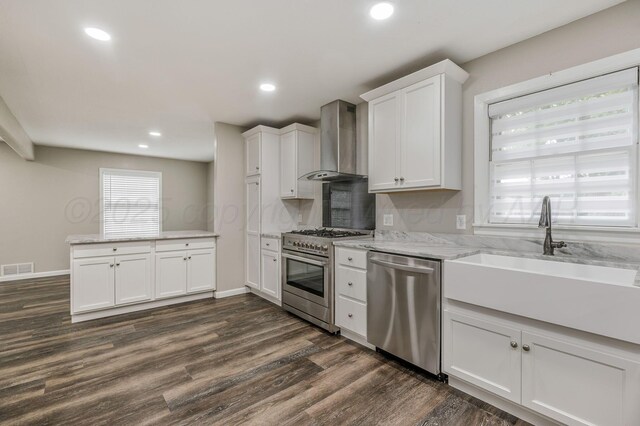 2421 Duncan St, Pampa, TX 79065 - kitchen featuring stainless steel appliances, wall chimney exhaust hood, a sink, dark wood-style flooring, and white cabinets