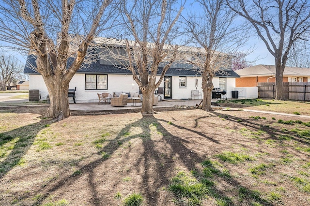 back of property with central air condition unit, a patio, roof with shingles, fence, and brick siding