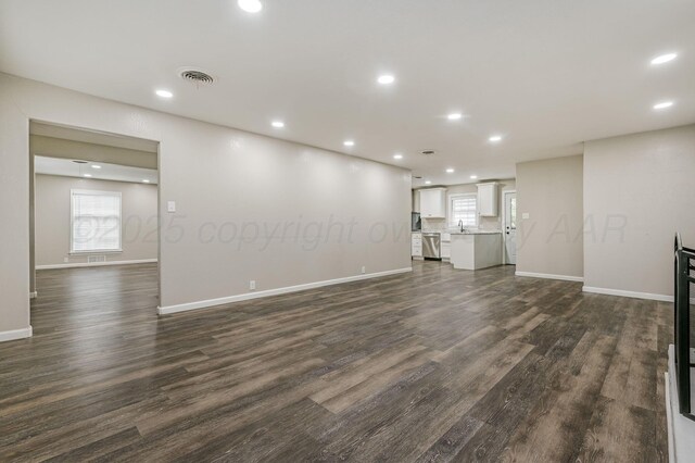 2421 Duncan St, Pampa, TX 79065 - unfurnished living room featuring dark wood-style flooring, baseboards, recessed lighting, a sink, and plenty of natural light
