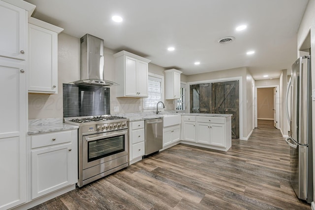 2421 Duncan St, Pampa, TX 79065 - kitchen with appliances with stainless steel finishes, wall chimney exhaust hood, dark wood-style flooring, white cabinets, and recessed lighting