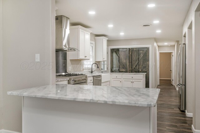 2421 Duncan St, Pampa, TX 79065 - kitchen featuring wall chimney range hood, appliances with stainless steel finishes, white cabinetry, light stone counters, and dark wood finished floors