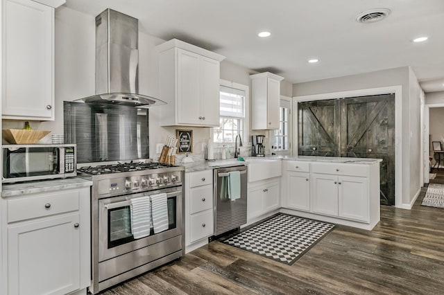 kitchen with dark wood finished floors, wall chimney range hood, visible vents, white cabinets, and appliances with stainless steel finishes