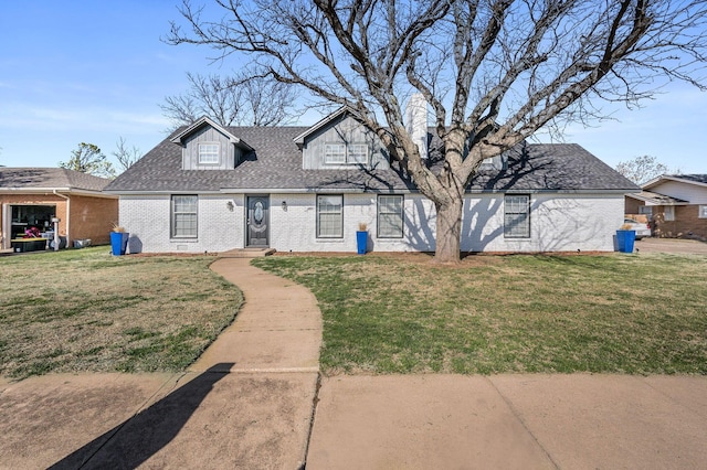 view of front of house featuring brick siding, a front yard, and roof with shingles