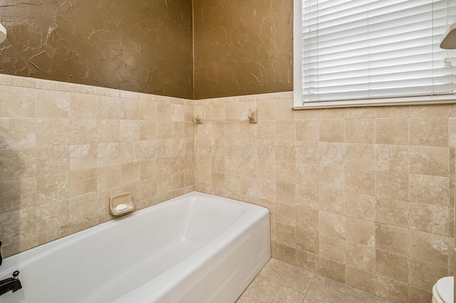 bathroom featuring toilet, tile walls, tile patterned flooring, and a bath