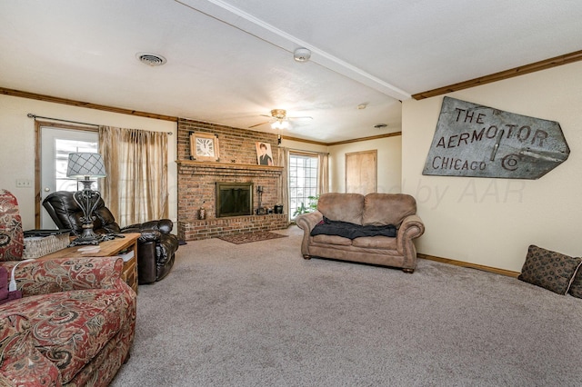 carpeted living room featuring a brick fireplace, crown molding, and ceiling fan