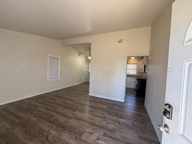 unfurnished room featuring lofted ceiling, visible vents, and dark wood-type flooring