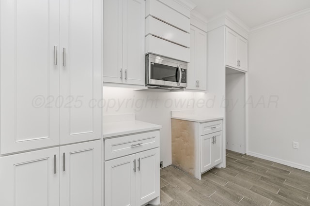 307 S Tennessee St, Amarillo, TX 79106 - kitchen with crown molding, white cabinets, light wood finished floors, light countertops, and stainless steel microwave