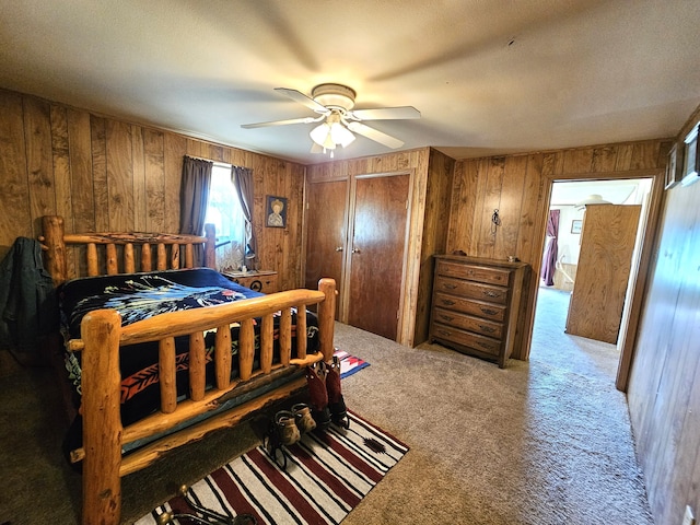 carpeted bedroom featuring wood walls, ceiling fan, and two closets