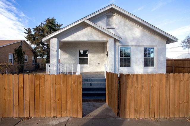 bungalow-style home featuring fence, brick siding, and covered porch