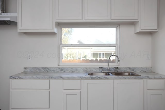 kitchen with a sink, light countertops, white cabinetry, and under cabinet range hood
