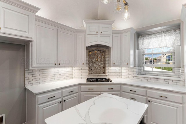 6501 Glenwood Dr, Amarillo, TX 79119 - kitchen featuring stainless steel gas stovetop, decorative backsplash, lofted ceiling, white cabinetry, and light stone countertops