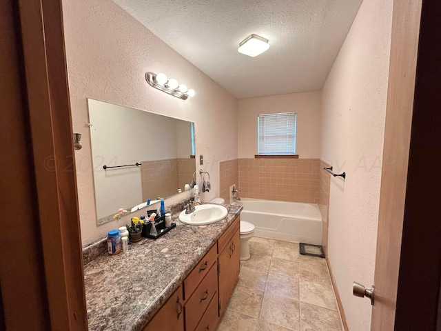 bathroom featuring toilet, a textured ceiling, vanity, a tub, and tile patterned flooring