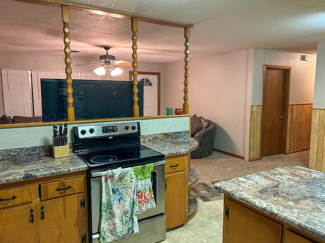 kitchen featuring electric stove, ceiling fan, a textured ceiling, and stone counters