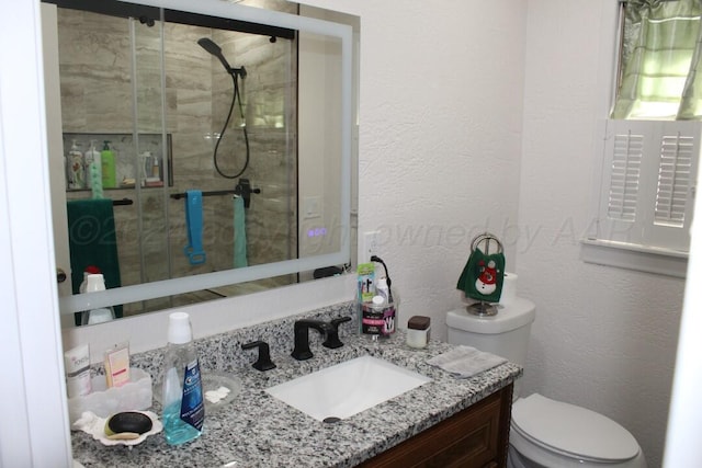 bathroom with a textured wall, a shower stall, toilet, and vanity