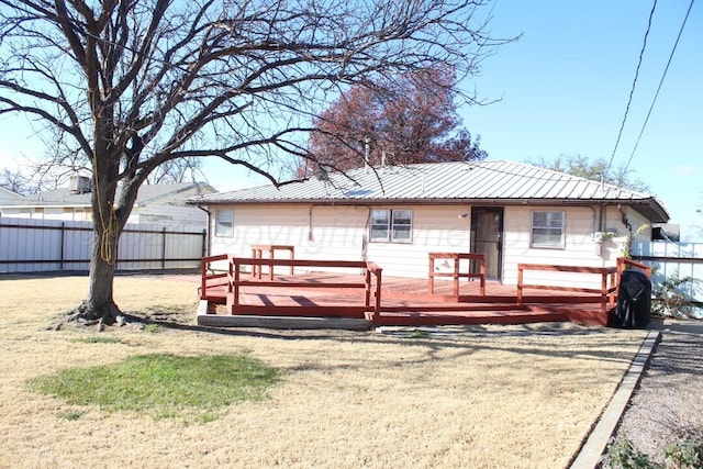 exterior space with a deck, metal roof, a yard, and fence